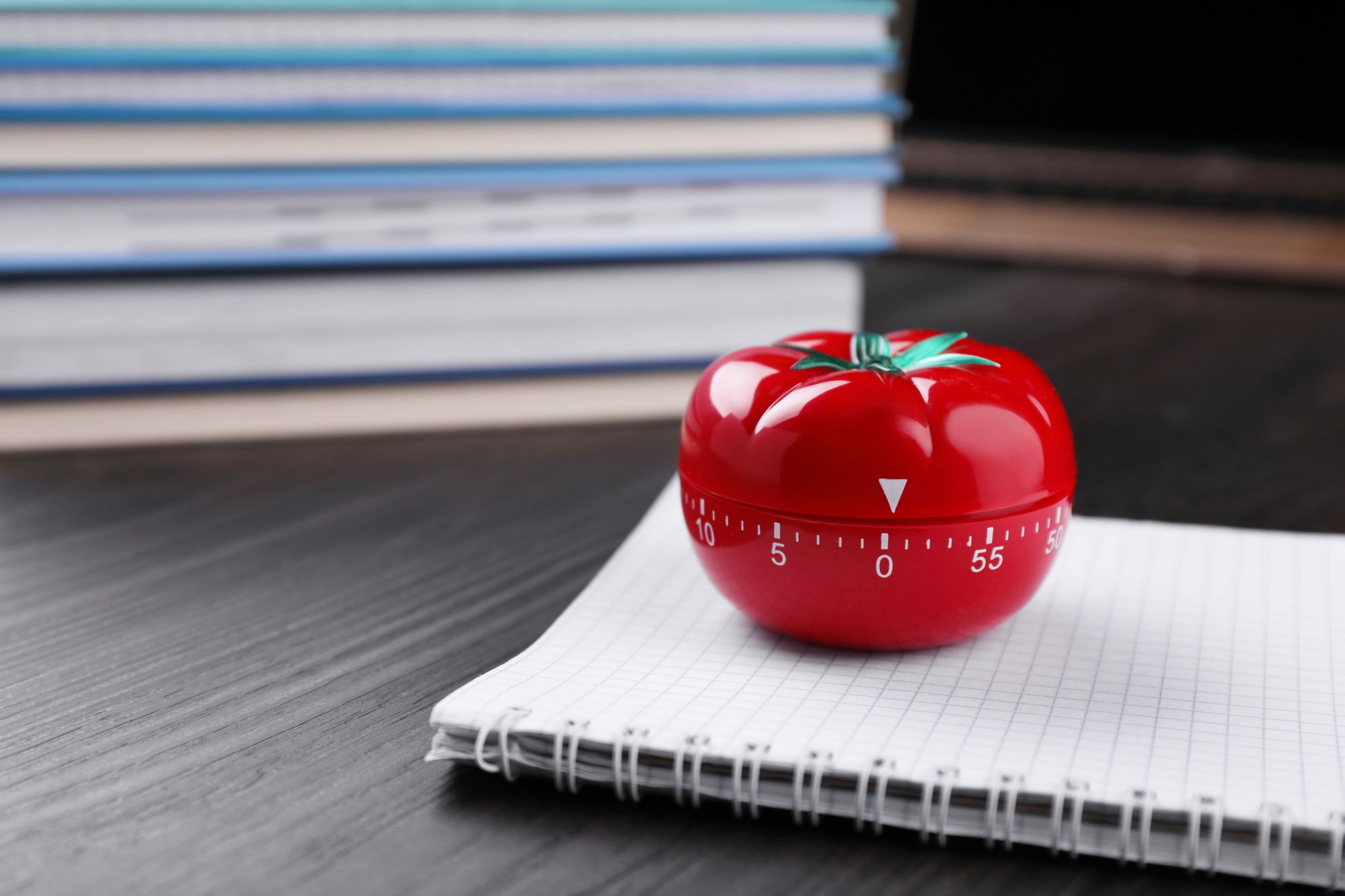 Tomato or pomodoro timer and notebook on wooden table