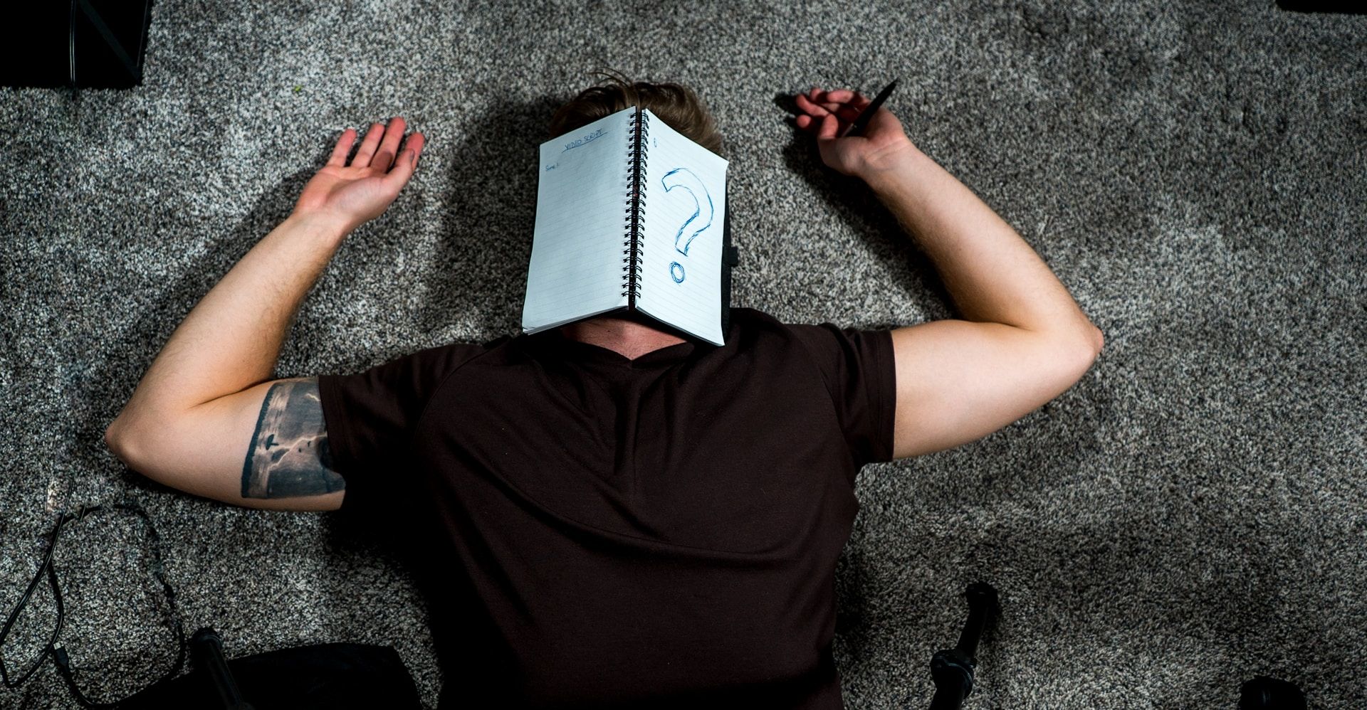 Student lying on the floor with a notebook on their face, representing lack of focus and study motivation.
