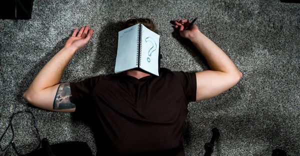 Student lying on the floor with a notebook on their face, representing lack of focus and study motivation.